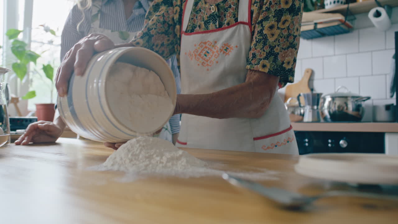 Elderly Woman Pouring Flour on Table as Teaching Granddaughter to Cook