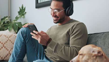 man, phone and headphones on sofa with dog