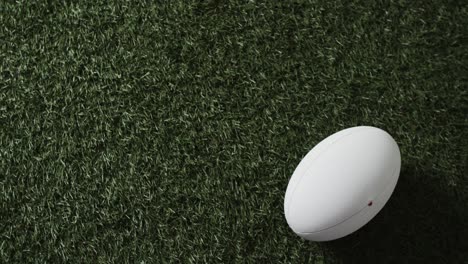 white rugby ball on sunlit grass with copy space, slow motion