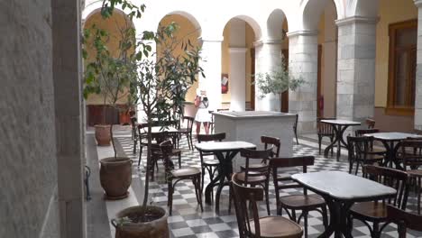 reveal shot of girl in dress and summer outfit walking through beautiful hall inside syros town hall and looking around slow motion