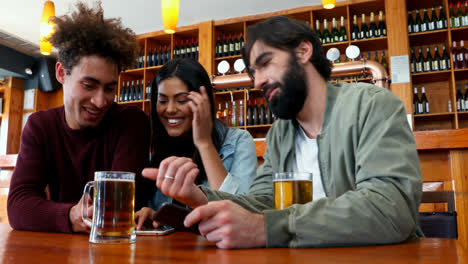 amigos usando el teléfono móvil mientras beben cerveza 4k