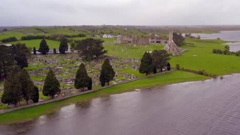 Suave-Paralaje-Aéreo-Del-Asentamiento-Clonmacnoise,-El-Cementerio-Y-El-Río-Shannon