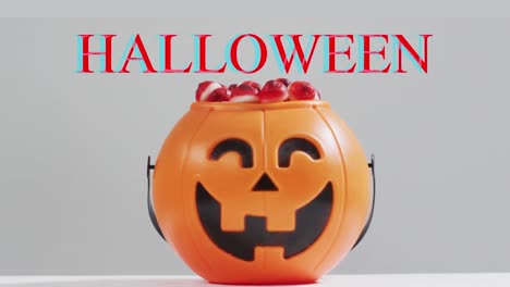 Animación-De-Texto-De-Halloween-Sobre-Cubo-De-Calabaza-Tallado-Con-Dulces-Sobre-Fondo-Gris