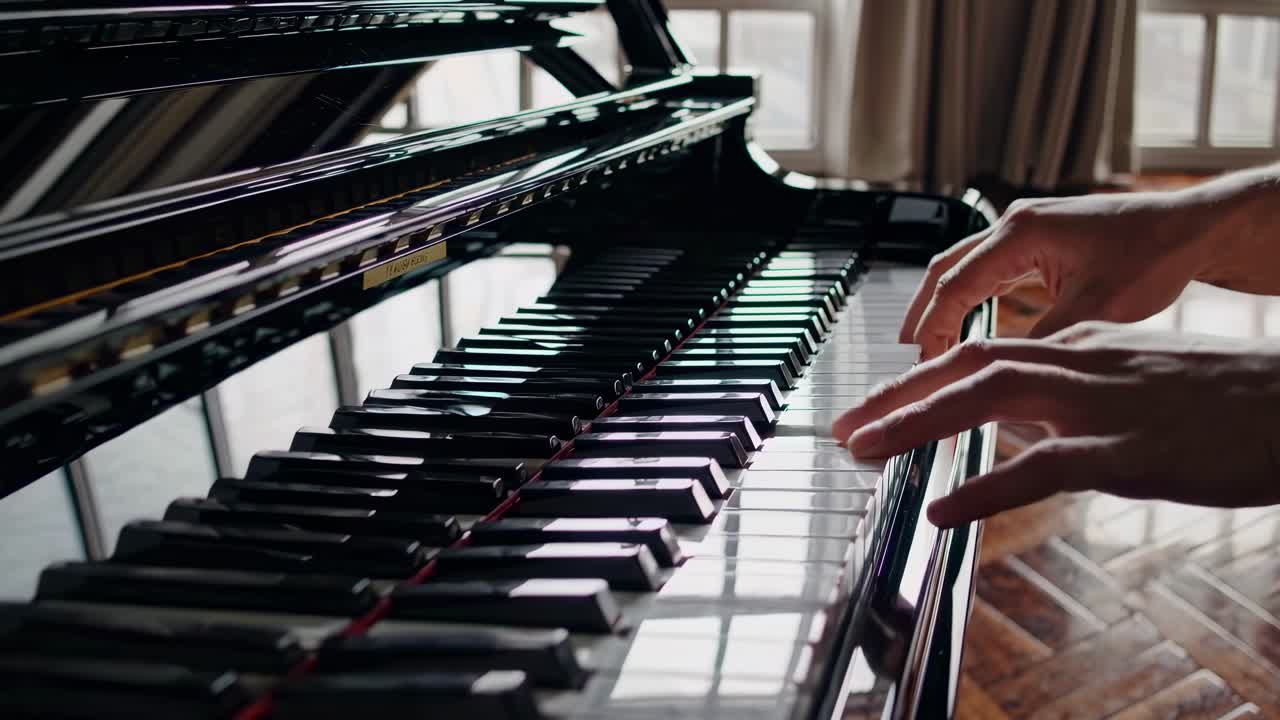 Close-up video of a grand piano's glossy keys, shot from a low angle, highlighting reflections