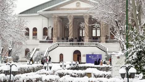 spiral marble stone column of a historical house palace in tehran wooden arch architectural design pavilion and heavy snow rarely event in iran people are visiting the monument in freezing winter