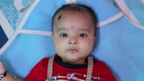 Säuglingsjunge-Liegt-Süßer-Gesichtsausdruck-Mit-Blauem-Hintergrund-Im-Innenbereich