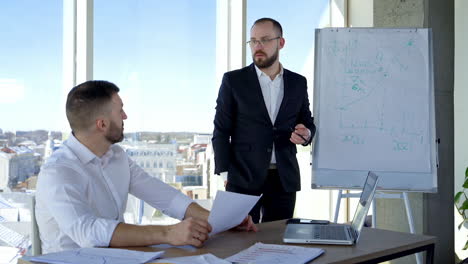 Male colleagues cooperating in office. Businessmen coworkers discussing together at workplace business project. Work of two employees making new ideas.