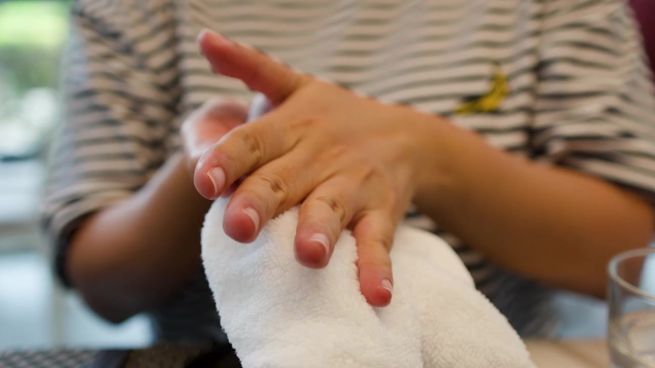 Primo piano di una donna che si pulisce le mani con un asciugamano bianco prima di cenare