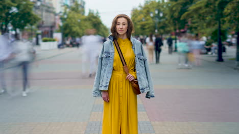woman in yellow dress and denim jacket on city street