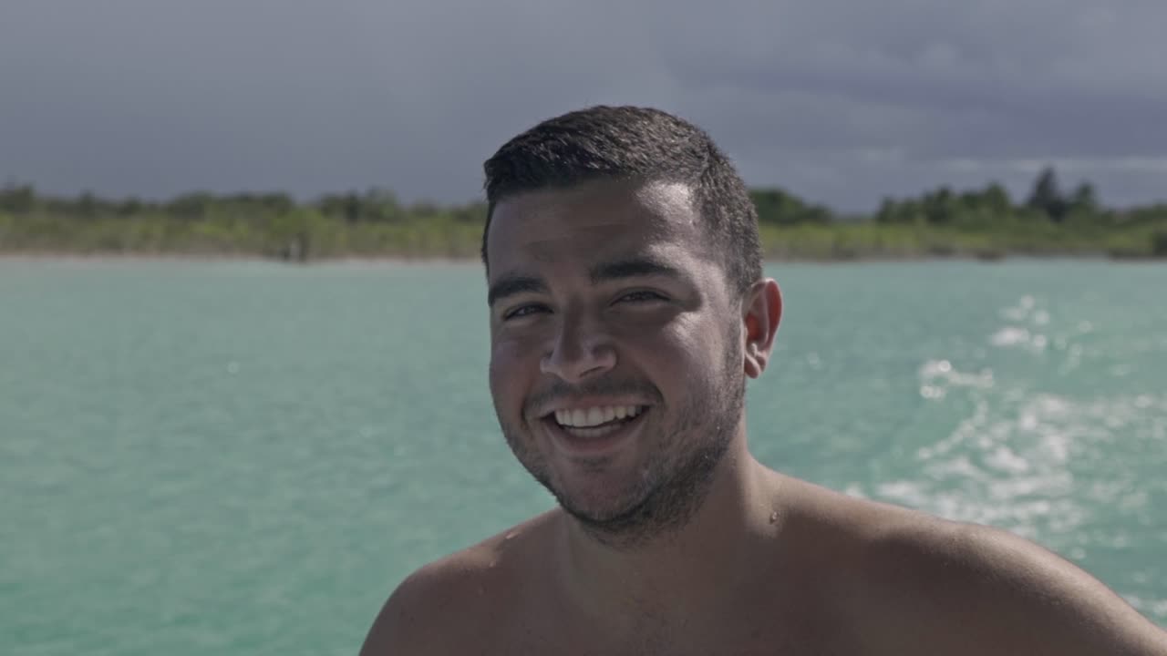 Man smiling while enjoying a boat ride on the stunning Laguna de Bacalar in Quintana Roo, México