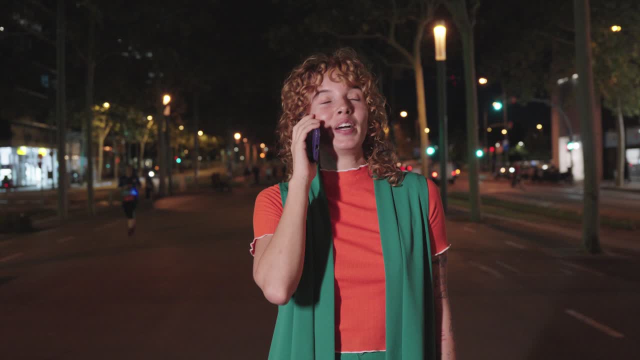 A woman talking on the phone at night on a city street