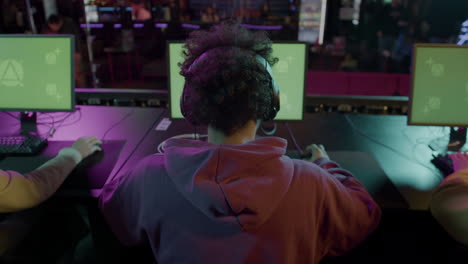 rear view of  team of cybersport gamers playing virtual video games on professional computer with green screen display