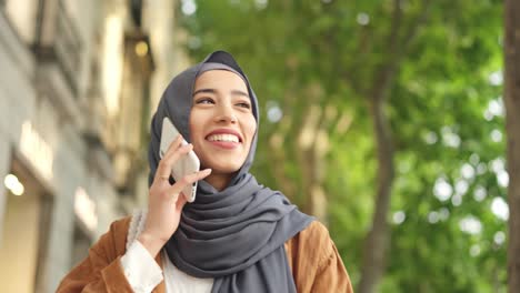 happy young muslim woman talking on smartphone outdoors