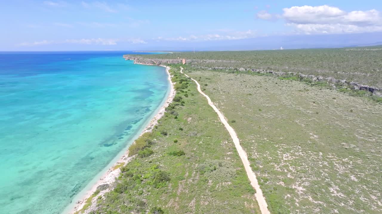 vuelo aéreo hacia adelante sobre la isla verde con camino a lo largo de la playa de arena y el mar turquesa del caribe - bahía de las águilas, pedernales