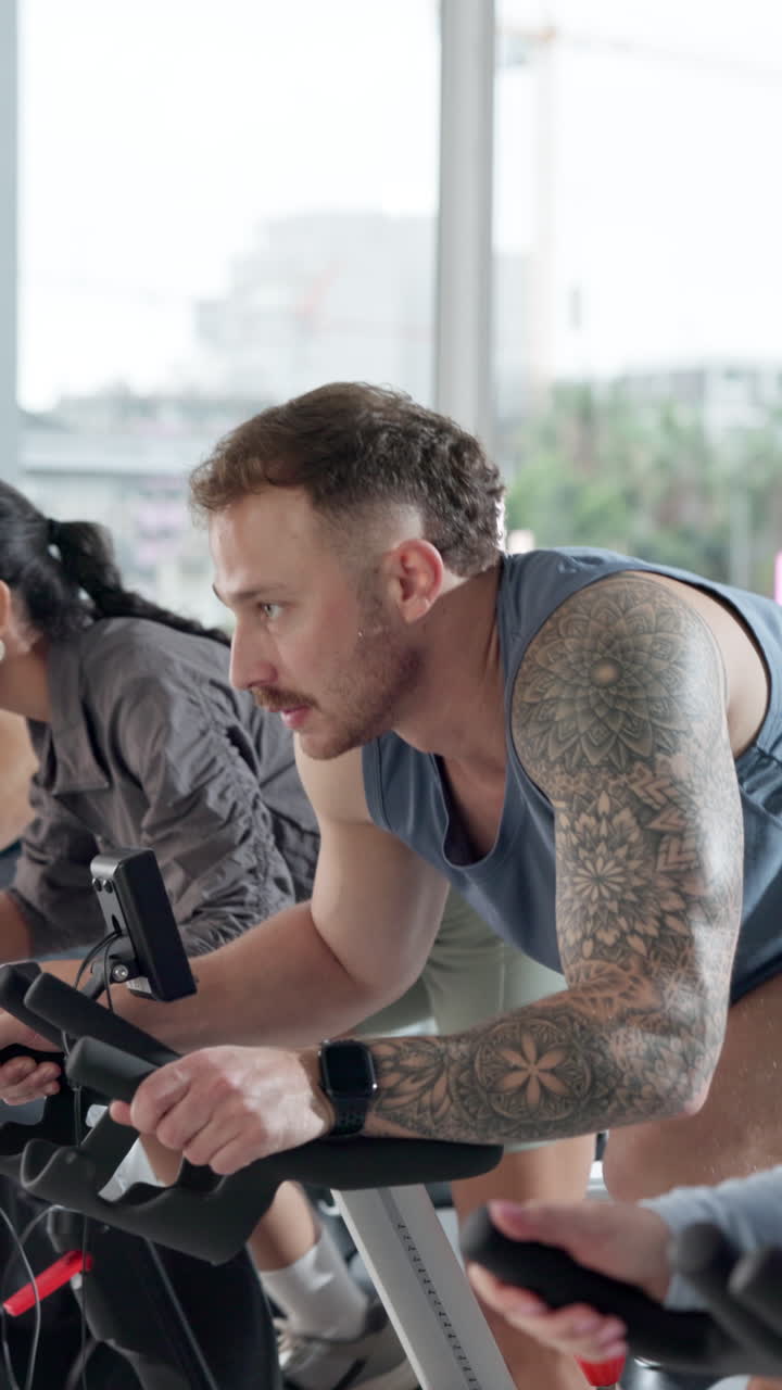 Man with Tattoos Cycling on Stationary Bike in a Gym