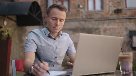 smiling man with works from home in his kitchen using a laptop. remote work and remote learning. remote work during self-isolation in quarantine man works with financial documents.