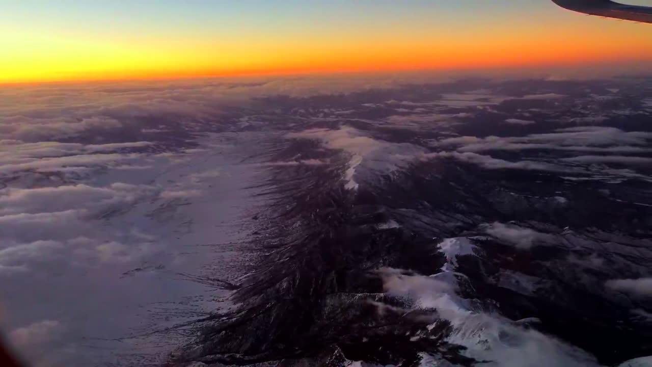 Flying over mountains in an Airplane at sunset.