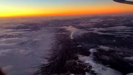 flying over mountains in an airplane at sunset.