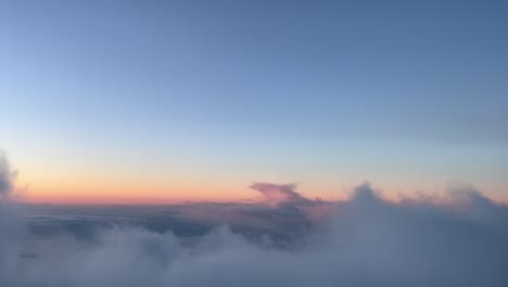 overflying some clouds in a cold winter sky just before sunrise, as seen by the pilots of an airplane