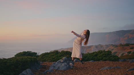 sensual performer dancing ocean landscape at summer evening. woman on cliff