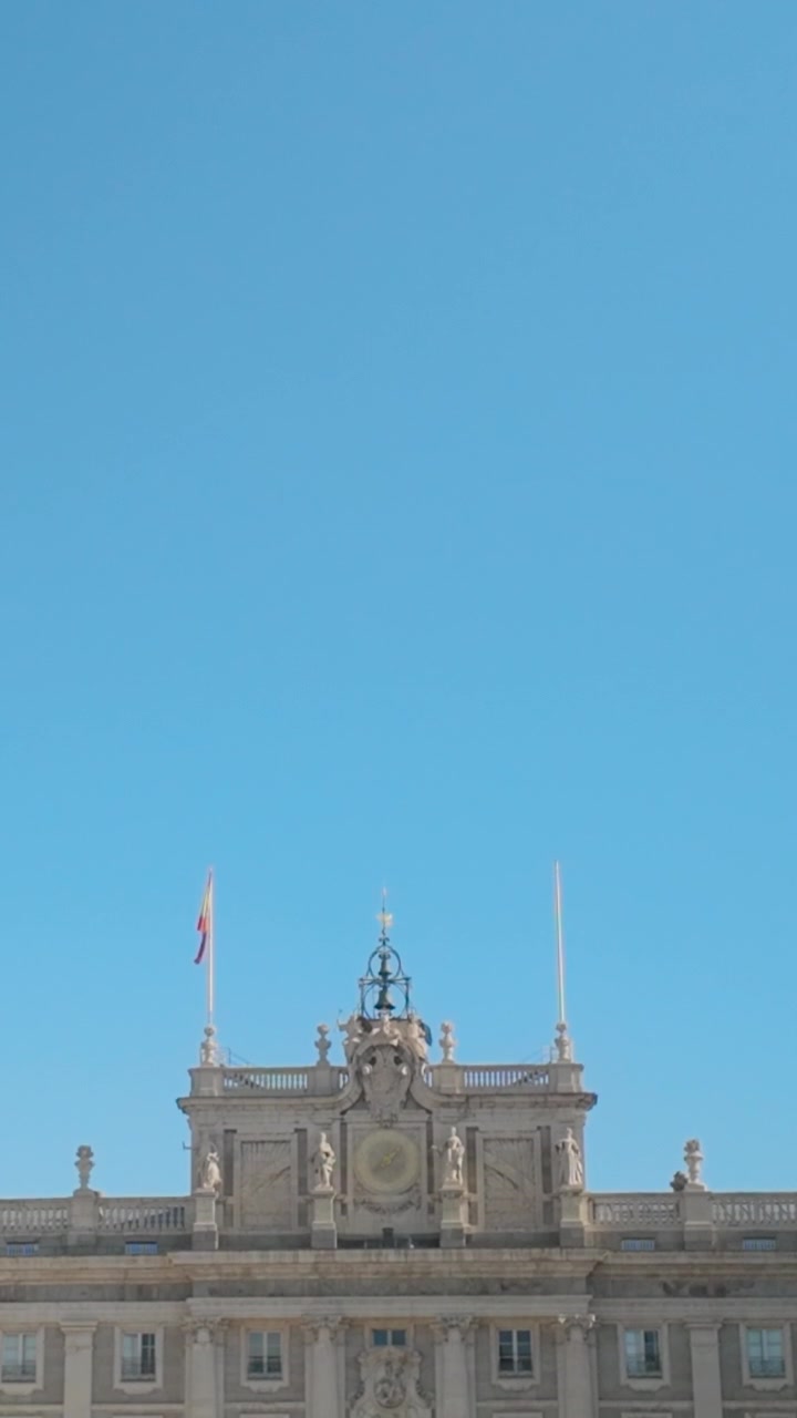 Ripresa verticale dal basso dell'architettura superiore decorata e del profilo del tetto del Palazzo Reale di Madrid sotto un luminoso cielo estivo. Adatto per documentari di viaggio e contenuti sul turismo spagnolo