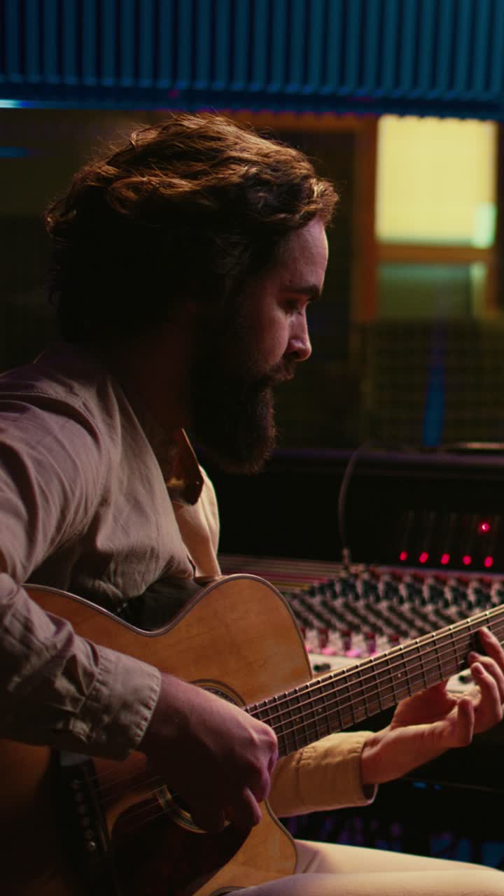 Uomo barbuto che suona la chitarra acustica in uno studio di registrazione musicale