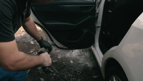 hombre limpiando un auto blanco con una lavadora a presión