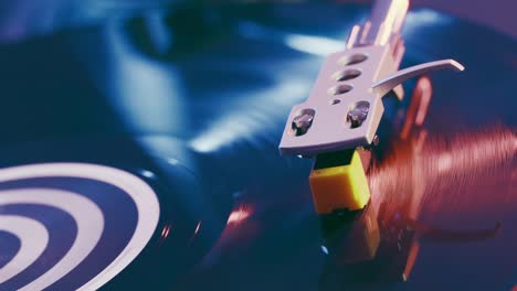 el tocadiscos de vinilo del reproductor en primer plano sobre un fondo de luces rojas y azules. fragmento de un reproductor de discos de vinilo negro giratorio