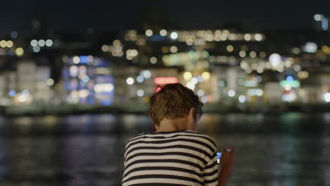 boy looking at smartphone at night city view