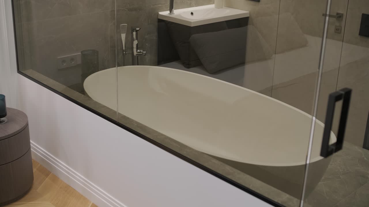 고급스러운 의자와  테이블을 가진 현대적인 침실의 아한 모이, 유리 파티션을 통해 볼 수 있는  화장실으로 이어지는 편안하고 정교한 도시 생활 공간을 구현합니다.