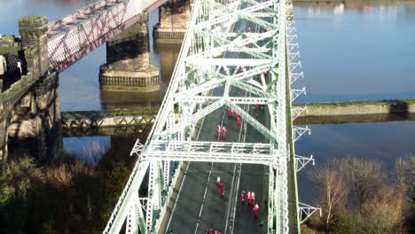 charity santa dash fun run over runcorn silver jubilee bridge aerial view fast tilting up