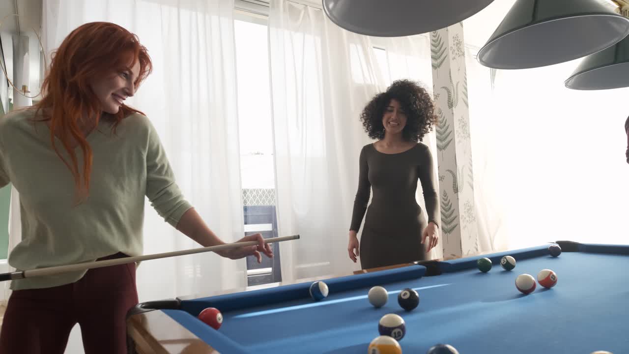 Happy woman playing pool with friends in game room on weekend