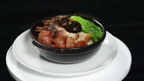 a person spinning a bowl with cooked meat and vegetables over a small plate - closeup shot