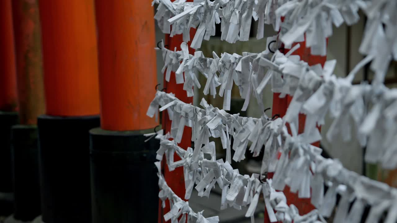 Wishing papers flutter gently in the breeze at Fushimi Inari Shrine, Kyoto.
