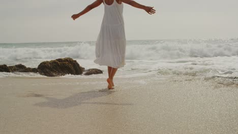 rear view of african american woman playing with sea water on the beach 4k