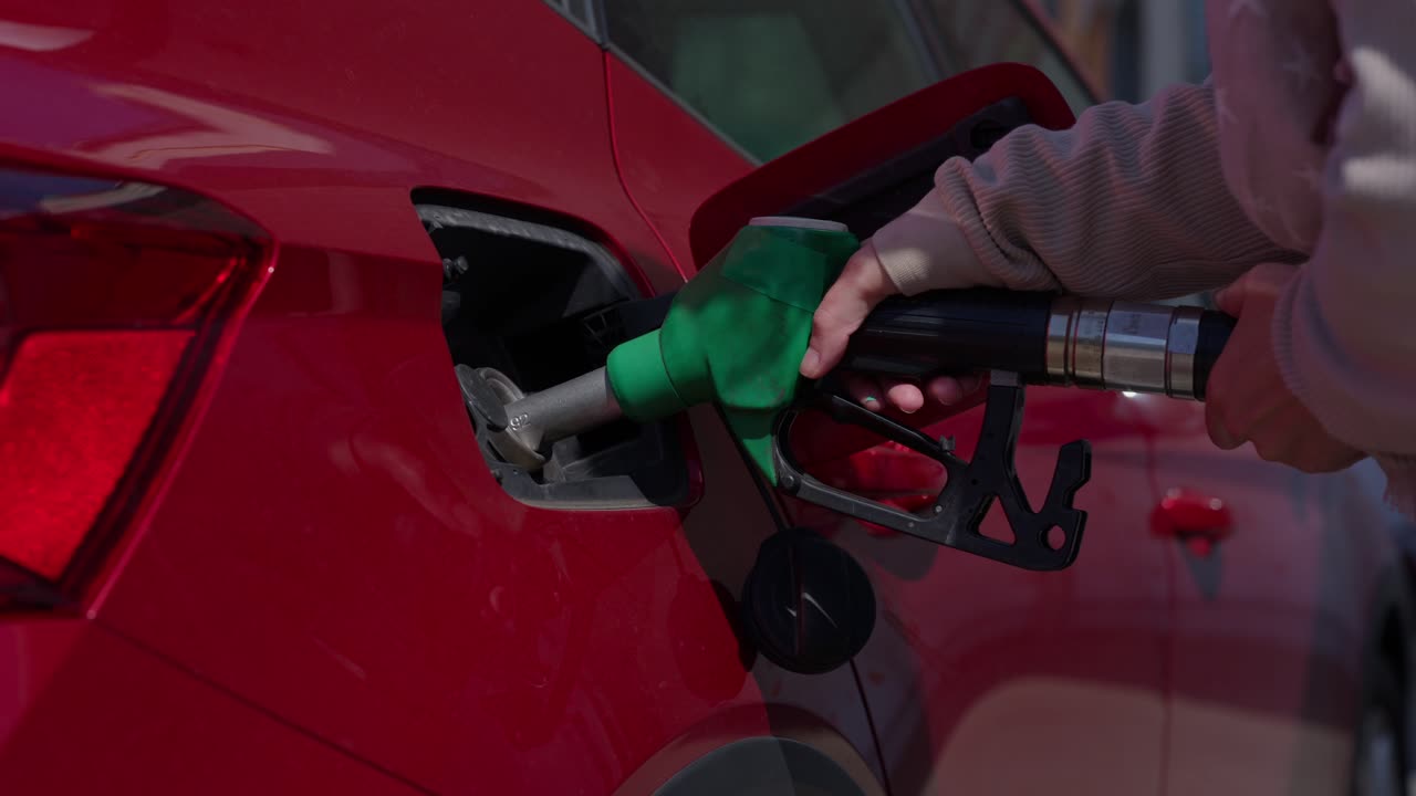 Persona che fa rifornimento a un'auto rossa in una stazione di servizio