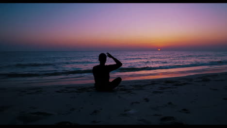 man meditating on the beach at sunset