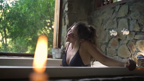 young attractive female having a fancy bath in a jacuzzi with big green nature window able to slow motion 60fps 3