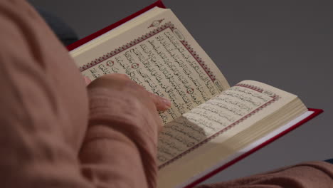 close up of muslim woman sitting on sofa at home reading or studying the quran 3