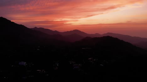 Fiery-sunset-above-small-village-in-deep-jungle-of-Colombia,-aerial-pan-left