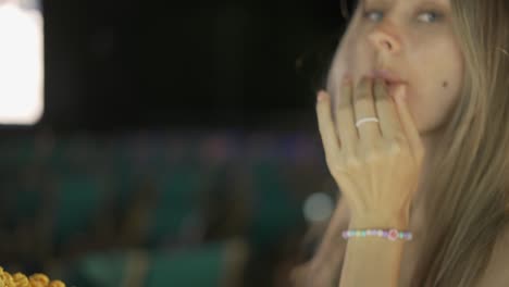 sonriente rubia encantadora tomando palomitas de maíz en el cine