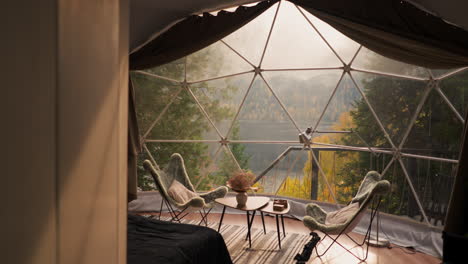 terraza de vidrio con vistas al lago de montaña de otoño. alojamiento moderno equipado con muebles acogedores para disfrutar de un fin de semana tranquilo. casa de glamping para turistas