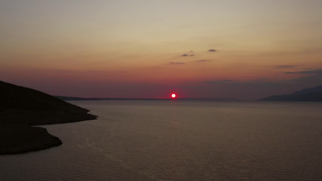 tiro de seguimiento izquierdo de la espectacular puesta de sol sobre el mar croata en calma, aéreo