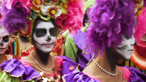 people wearing bright colorful outfits and sugar skull makeup at the day of the dead parade in mexico city, 2019. the day of the dead is a mexican holiday where the dead are celebrated across two days