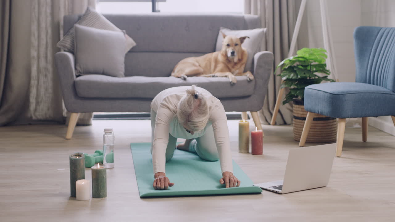 Voksen kvinne som praktiserer yoga mens hun ser på