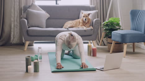 mature woman practicing yoga while watching