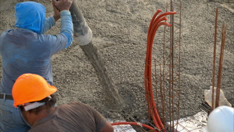 movimiento lento de un trabajador de la construcción latino mexicano irreconocible usando una bomba de boom para aplicar mezcla de hormigón en una cuadrícula con estiroespuma para construir el piso de losas de una casa nueva