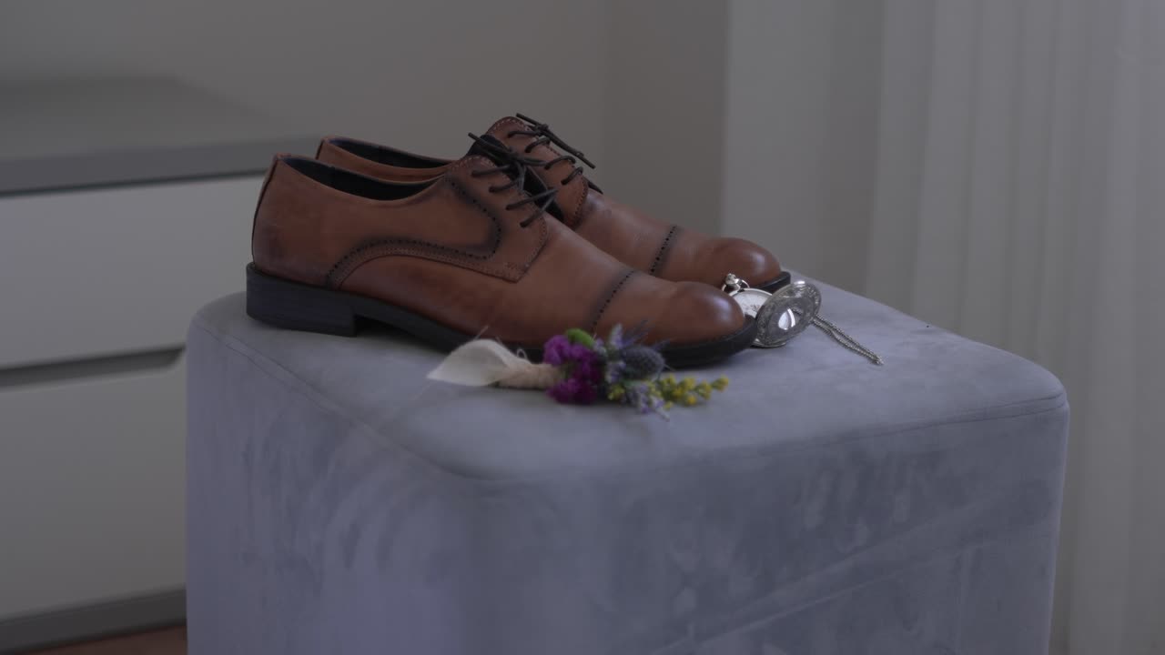 classic brown shoes boutonnière and pocket watch arranged neatly before wedding ceremony