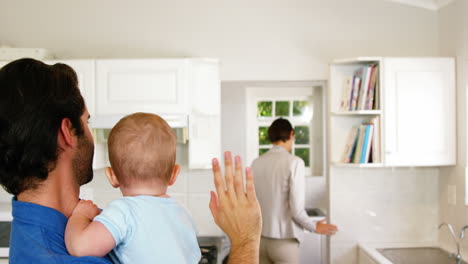 father holding his baby and saying bye to his wife