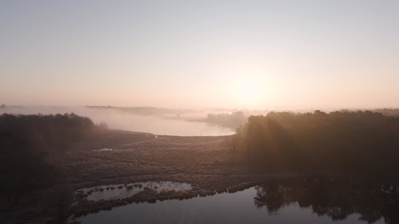 amanecer brumoso sobre un lago y un bosque